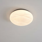 A small black-rimmed Clérachic ceiling light lit with a white ribbed shade against a grey ceiling.