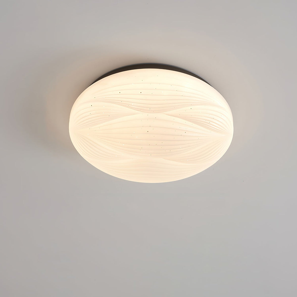 A small black-rimmed Clérachic ceiling light lit with a white ribbed shade against a grey ceiling.