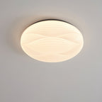 Lit Clérachic ceiling light with a dark rim and a ribbed white shade, seen from below on a grey ceiling.