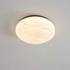 Lit Clérachic ceiling light with a black rim and a softly ribbed white shade, seen from the side on grey.