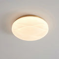 Close angle on a lit, gold-rimmed Clérachic ceiling light with its deeper ribbed white shade on a grey ceiling.