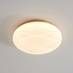 A larger, gold-rimmed Clérachic ceiling light lit with a smooth ribbed white shade, against a grey ceiling.