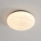 A larger Clérachic ceiling light with a black rim, its ribbed white shade lit evenly on a grey ceiling.