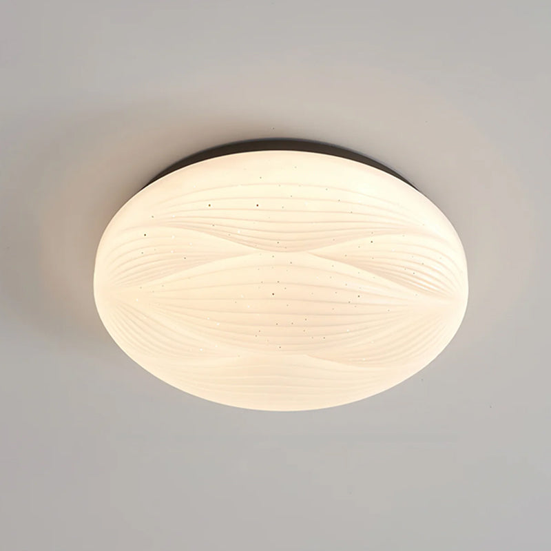 A larger Clérachic ceiling light with a black rim, its ribbed white shade lit evenly on a grey ceiling.