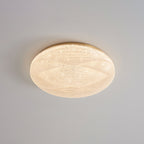Lit Clérachic ceiling light with a gold rim and a sparkly, crystal-textured shade on a grey ceiling.