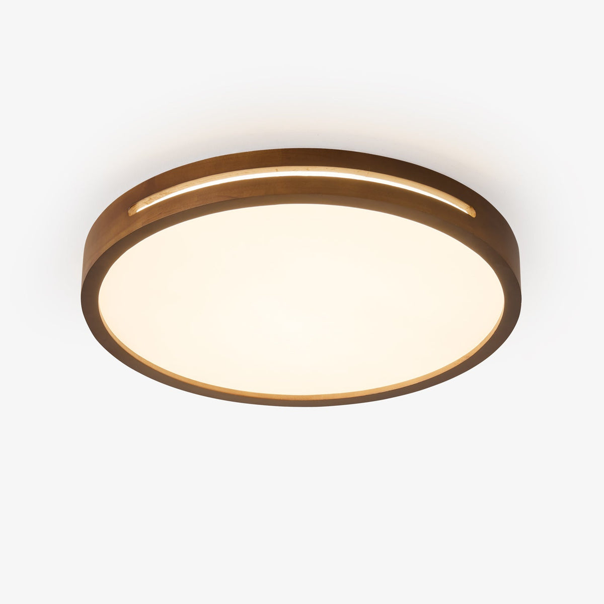 Round walnut-wood ceiling light from Clérachic with a frosted panel, lit warm and seen from below against a pale backdrop.