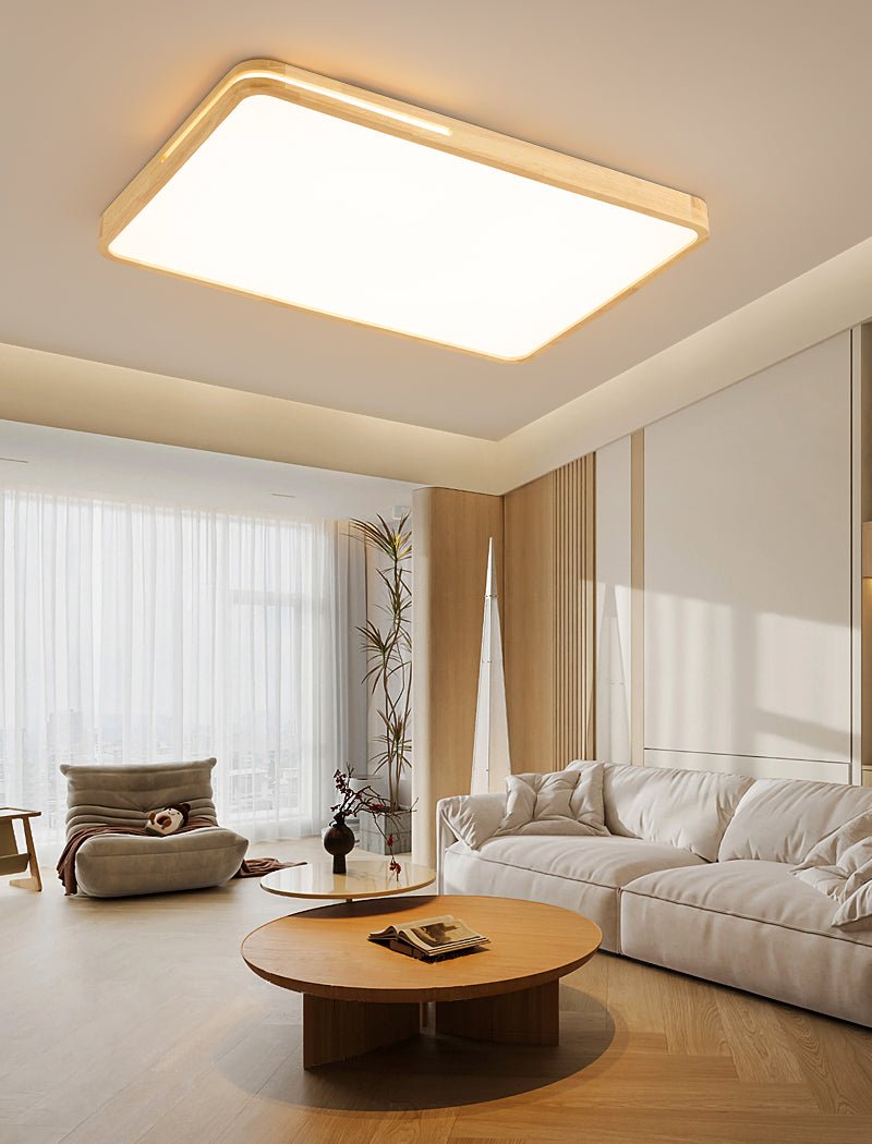 Rectangular Clérachic ceiling light with a pale wood frame glowing over a living room with a round coffee table and cream sofa.