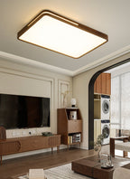 Dark wood rectangular ceiling light from Clérachic above a living room with a wall-mounted television and a walnut sideboard.