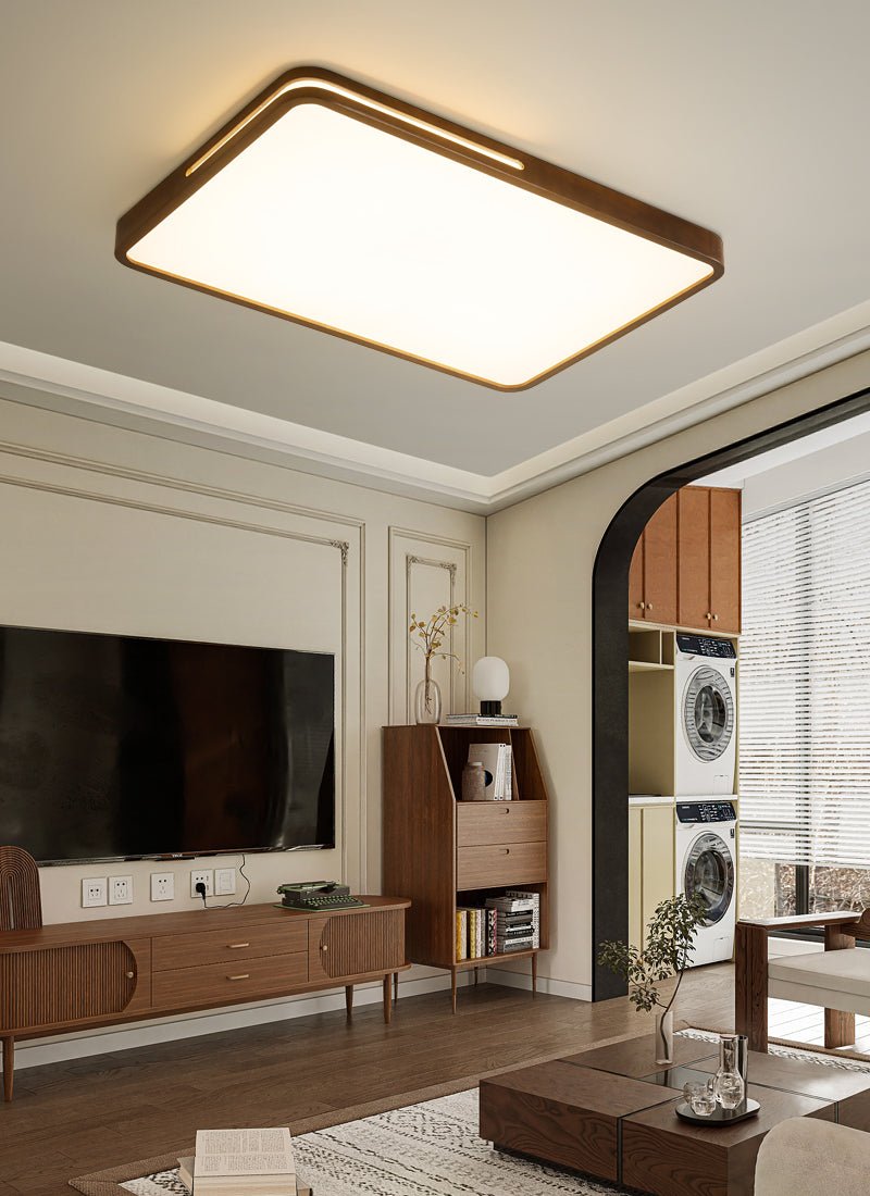 Dark wood rectangular ceiling light from Clérachic above a living room with a wall-mounted television and a walnut sideboard.