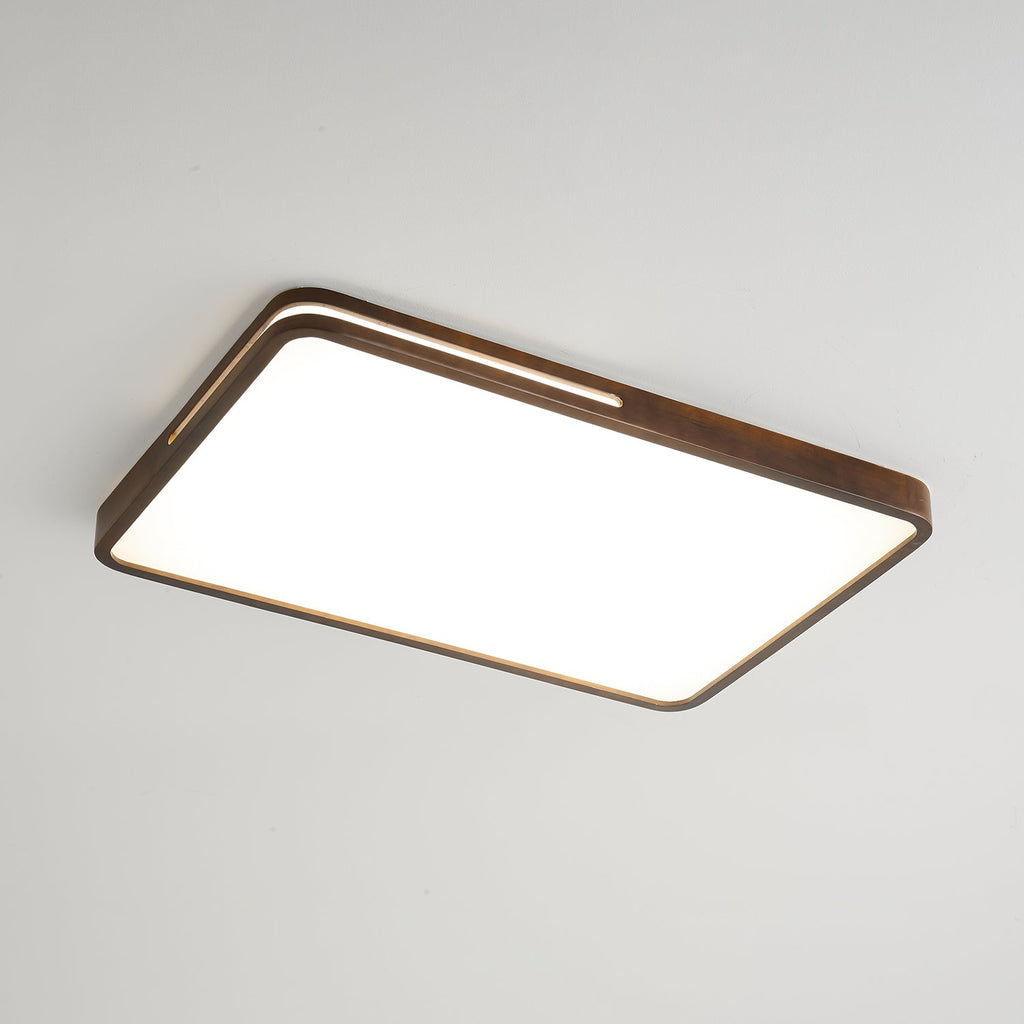 Rectangular walnut-frame Clérachic ceiling light lit cool white, with a slim slot along the rim, on a grey ceiling.