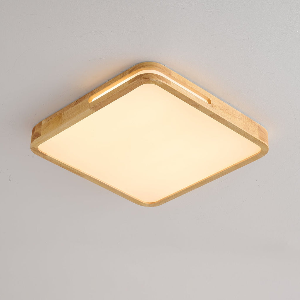 Square ceiling light from Clérachic with a pale wood frame and a warm glow across the panel, on a light grey ceiling.