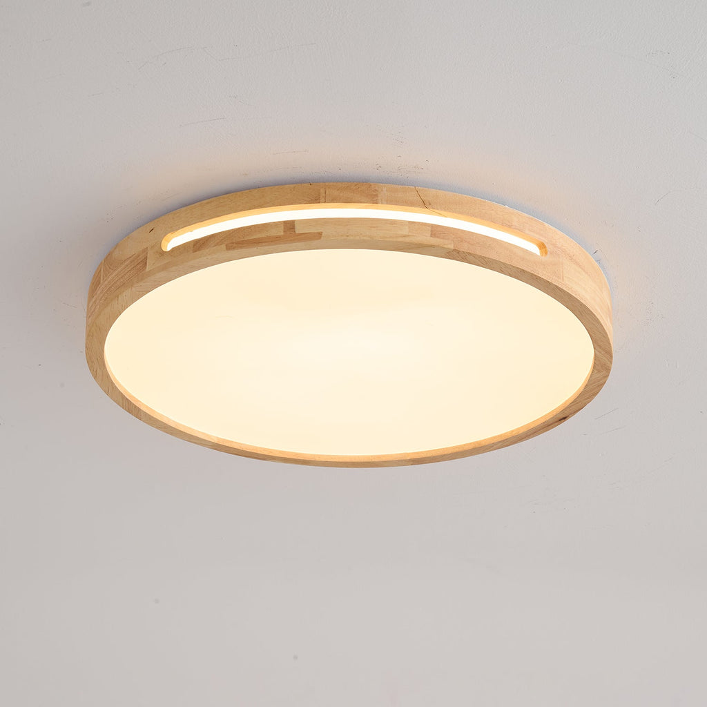 Close three-quarter view of a round light wood Clérachic ceiling light with a soft amber glow and a visible slot.