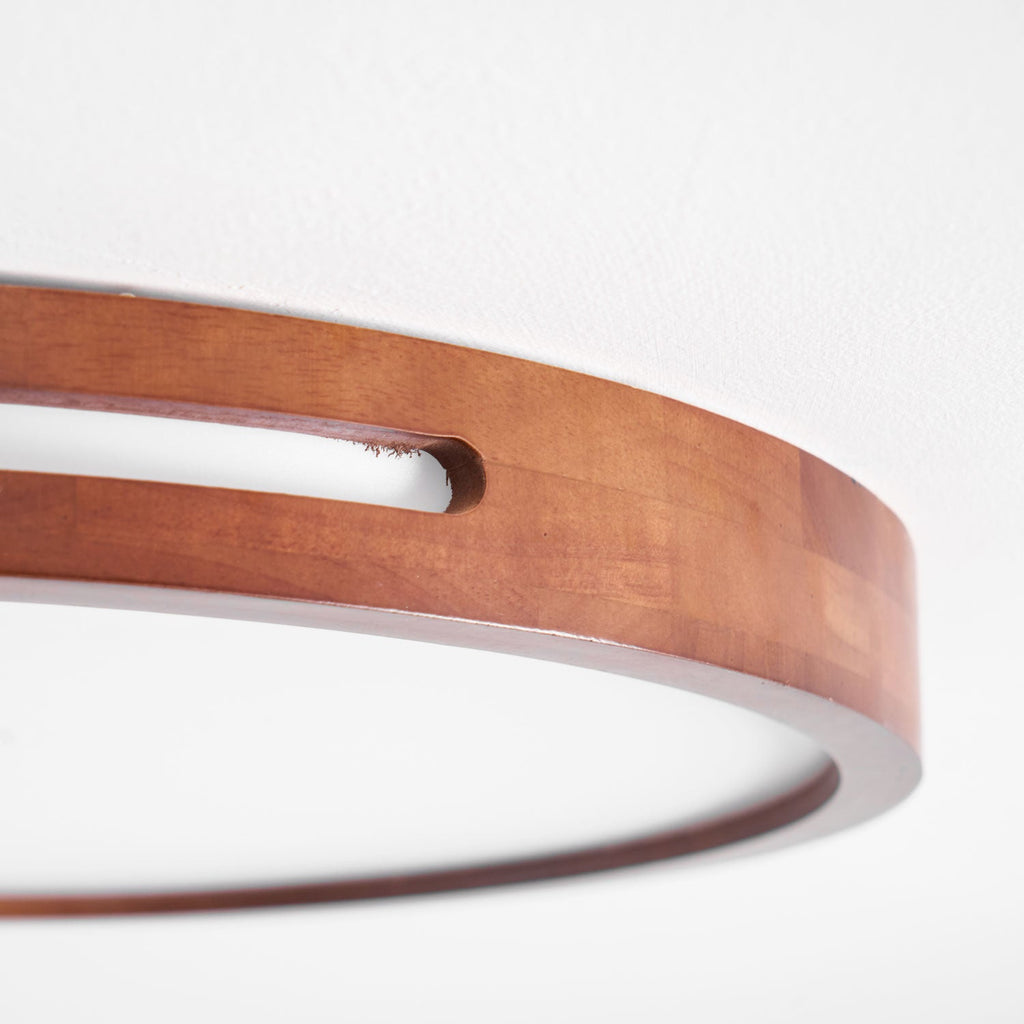 Close view of the glued walnut timber blocks and the long rim slot on this Clérachic ceiling light, above the frosted panel.