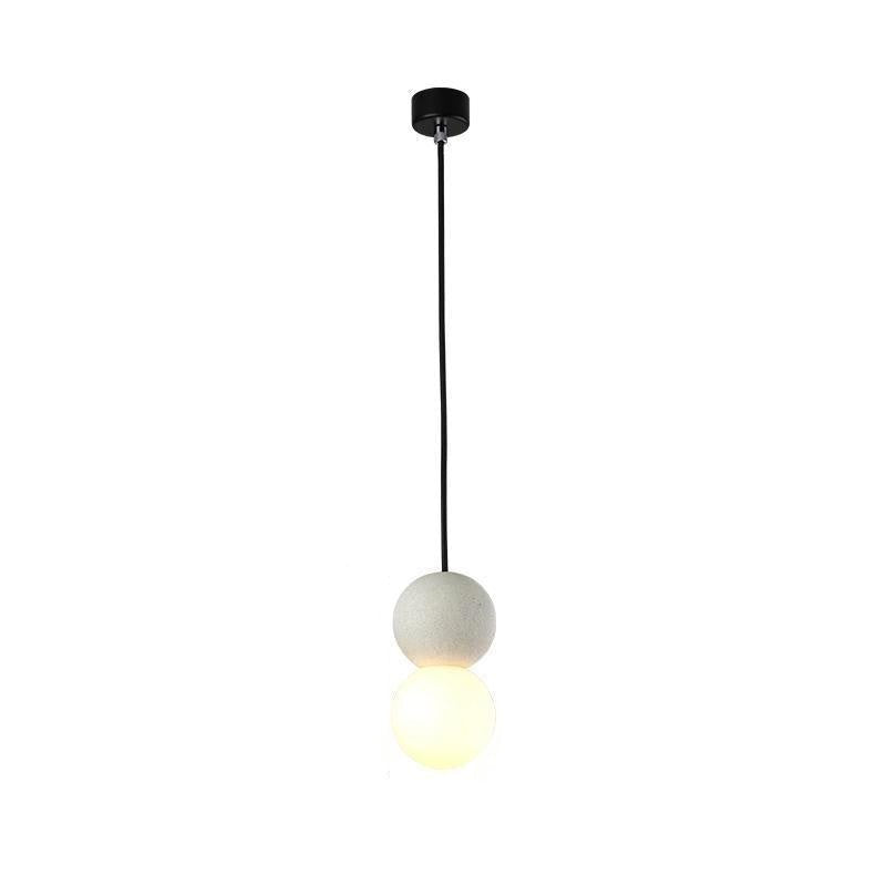 This Clérachic pendant, a pale stone-textured sphere above an opal glass globe, hangs on a black cord against a white background.