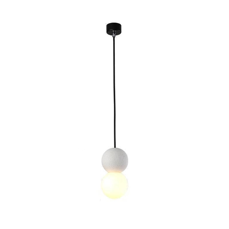This Clérachic pendant, a pale stone-textured sphere above a lit opal glass globe, drops from a black ceiling canopy on white.