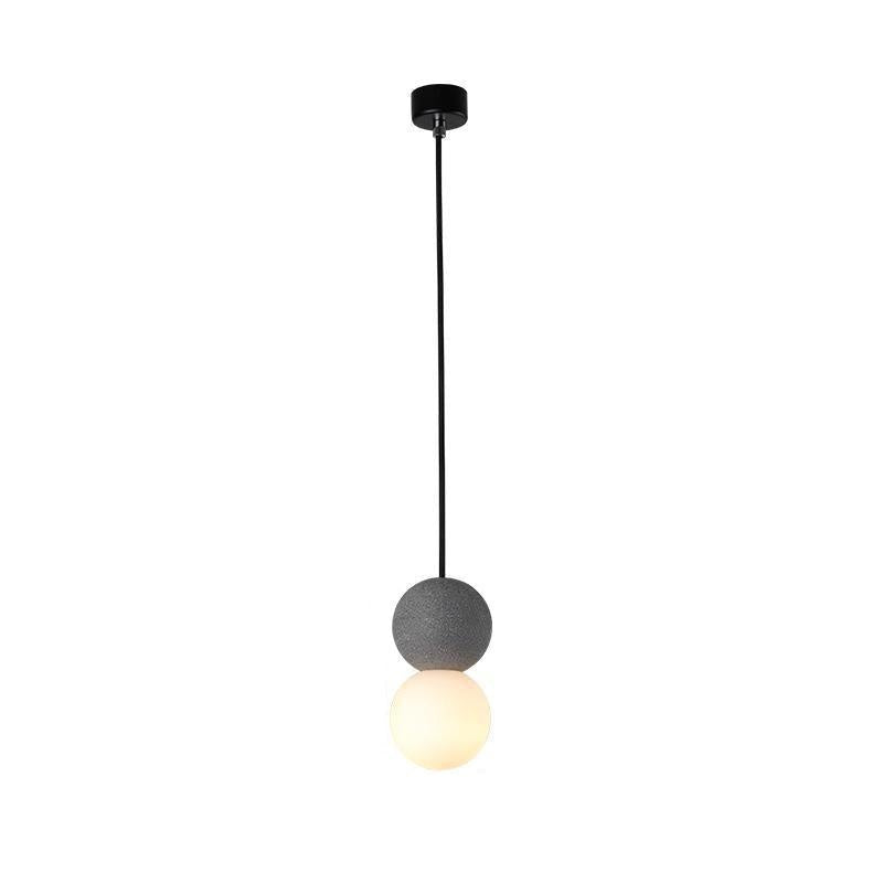 This Clérachic pendant, a grey stone-textured sphere above an opal glass globe, hangs from a black ceiling canopy against white.