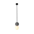This Clérachic pendant, a grey stone-textured sphere above an opal glass globe, hangs from a black ceiling canopy against white.