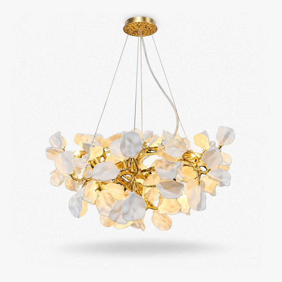 A Clérachic chandelier of layered white ceramic petals on a gold-tone vine frame, lit warmly and shown on a plain white backdrop.