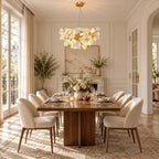 A Clérachic chandelier hangs over a long walnut dining table set for dinner, in a panelled room with French doors.