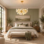 This Clérachic chandelier lit in a bedroom with sage-green panelling, a white bed, a linen bench and a landscape painting.