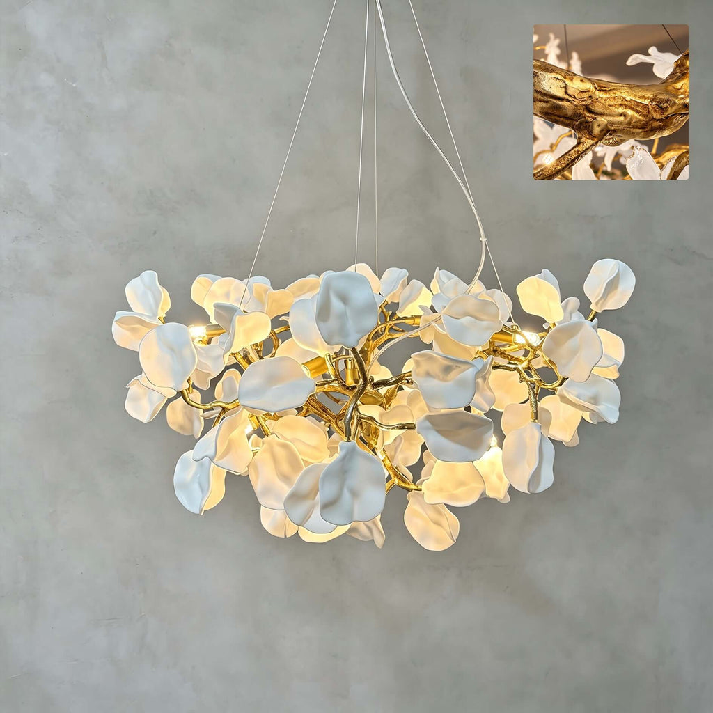 The Clérachic chandelier lit against a grey plaster wall, its ceramic petals clustered on a gold vine, with a small detail inset.