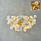 A Clérachic chandelier lit against a grey wall, with soft white ceramic petals on a gold vine and an inset close-up of the branch.