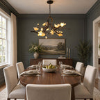 A Clérachic chandelier lit against a dark slate-blue panelled wall, above an oval wood table set for dinner.