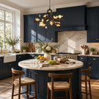 Clérachic chandelier lit over a round marble-topped island in a navy-blue kitchen, with woven wooden stools in front.