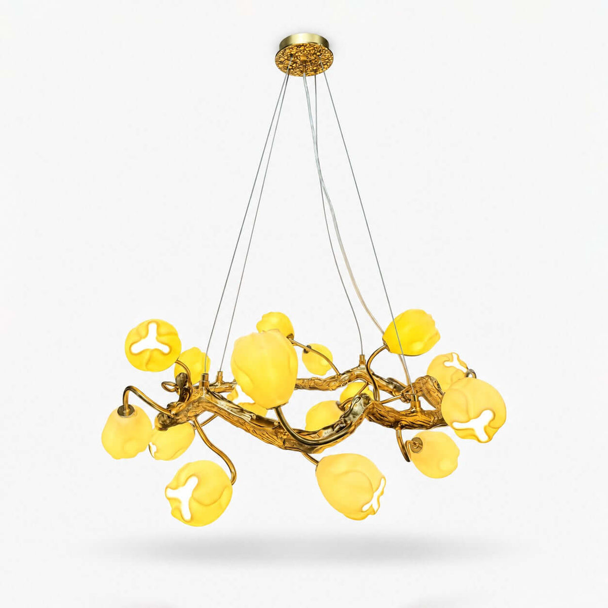 Gold branch chandelier from Clérachic with softly lit yellow-white flower shades on a ring of twisting stems, hung on thin cables against white.