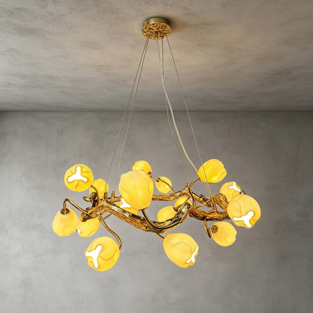 Close, upward view of this Clérachic gold branch chandelier lit against a grey plaster ceiling, its flower shades glowing yellow-white.