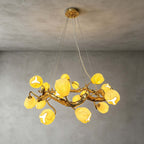 Close, upward view of this Clérachic gold branch chandelier lit against a grey plaster ceiling, its flower shades glowing yellow-white.