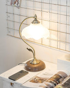 Clérachic table lamp lit on a marble-topped surface, with a phone and an open magazine in front of a metal wall grid.