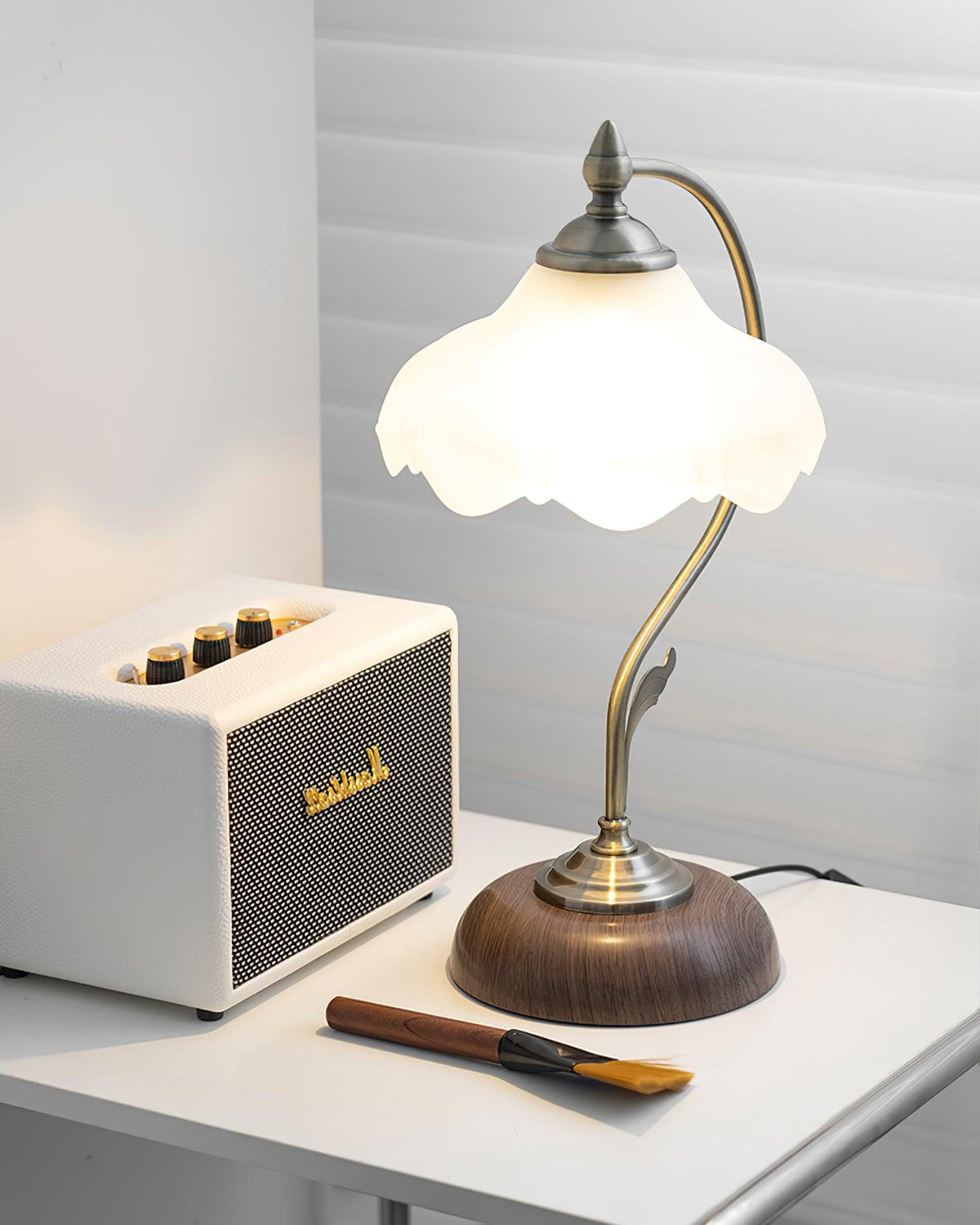 Lit Clérachic table lamp next to a cream retro speaker on a white desk, with a small wooden brush lying in front.