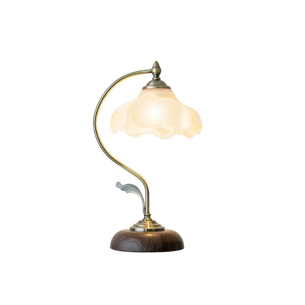 Lit Clérachic table lamp with a frosted glass flower shade and a leaf detail on its arm, shown on a white backdrop.