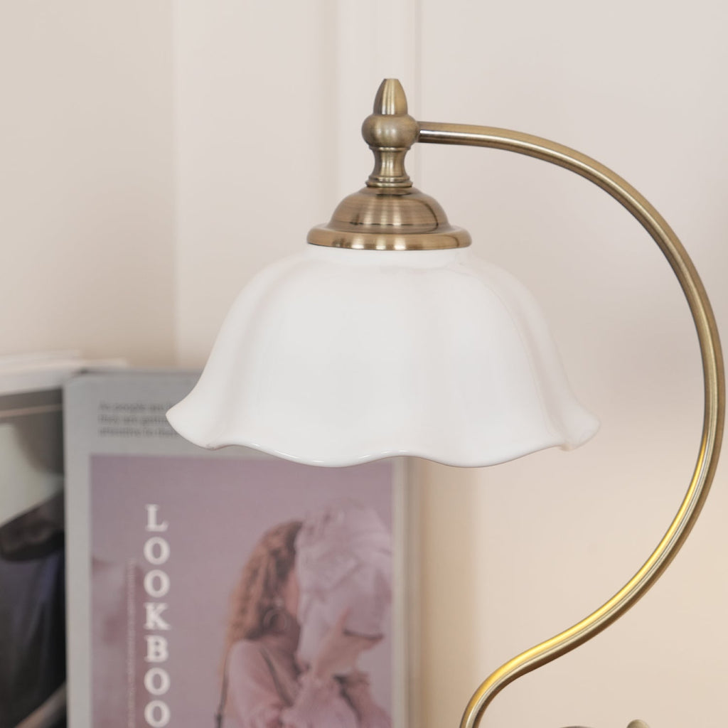 Close view of the white ceramic shade and brass-toned finial on this Clérachic table lamp, with a lookbook blurred behind.