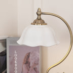 Close view of the white ceramic shade and brass-toned finial on this Clérachic table lamp, with a lookbook blurred behind.