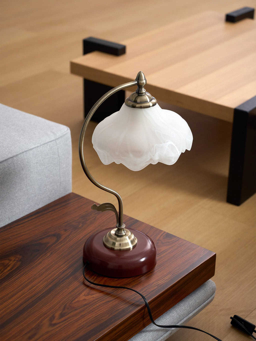 Unlit frosted glass Clérachic table lamp on a dark wood side table beside a pale grey sofa and a light oak coffee table.