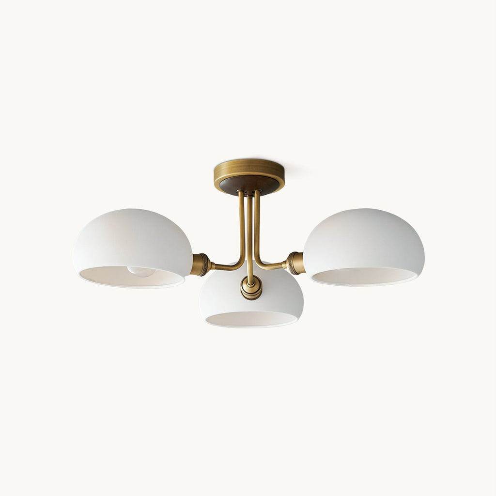 Three white ceramic domes on an antique brass arm, this Clérachic flush-mount ceiling light shown on a plain white backdrop.