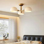 Lit ceiling light from Clérachic above a bed with a dark tufted headboard, beside a window with sheer curtains.