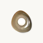This Clérachic ceramic wall light on a plain white backdrop, a pebble-shaped taupe dish with a round white glass globe at its centre.
