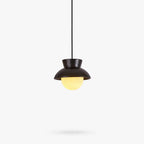 A black ceramic Clérachic pendant with a flared hood and a ribbed, softly lit glass globe below, on a plain white backdrop.