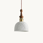 A white ceramic Clérachic pendant with a rose pattern in relief, a brass-coloured collar and a turned walnut top, on white.