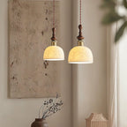 Two Clérachic pendants with rose-pattern ceramic shades lit side by side, in front of a textured wall panel.