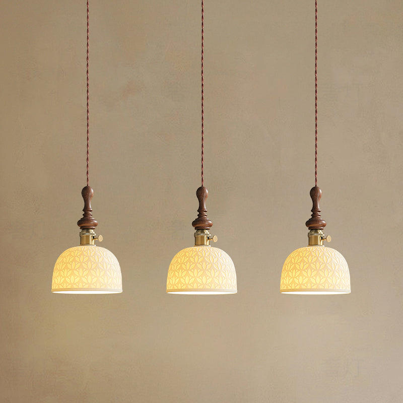 Three dome-shaped Clérachic pendants with a pierced star pattern, lit and hung on twisted cords against a plaster wall.