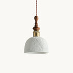 A white ceramic Clérachic pendant with a rose pattern, a brass-coloured collar and a turned walnut top, on a white backdrop.