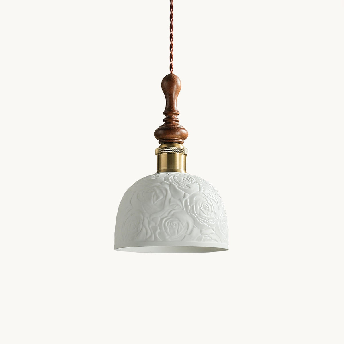 A white ceramic Clérachic pendant with a rose pattern, a brass-coloured collar and a turned walnut top, on a white backdrop.