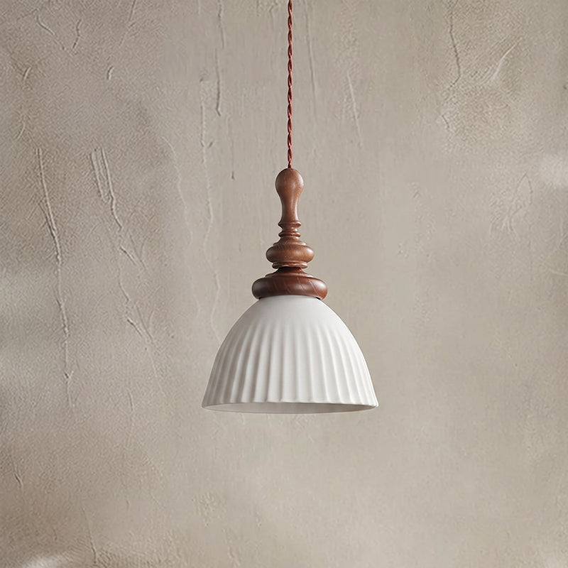 A white ribbed ceramic Clérachic pendant, unlit, with a turned walnut top, against a textured plaster wall.