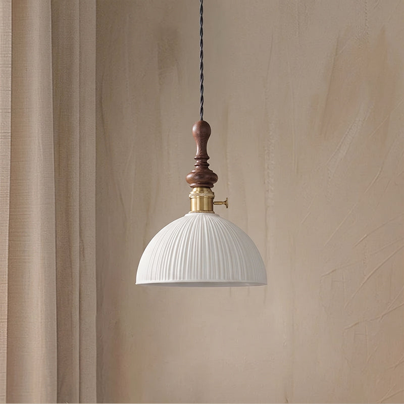 A white ribbed ceramic Clérachic pendant with a brass switch collar and a black cord, unlit, beside a linen curtain.
