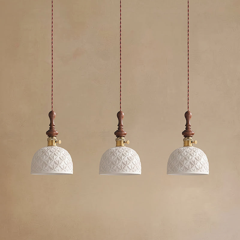 Three white ceramic Clérachic pendants with a pierced star pattern and brass switch collars, hung on twisted cords.
