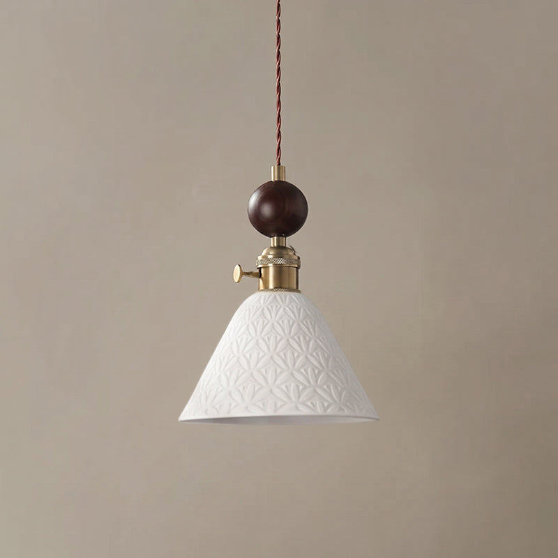A cone-shaped white ceramic Clérachic pendant with a star pattern in relief, under a round walnut ball and brass switch.